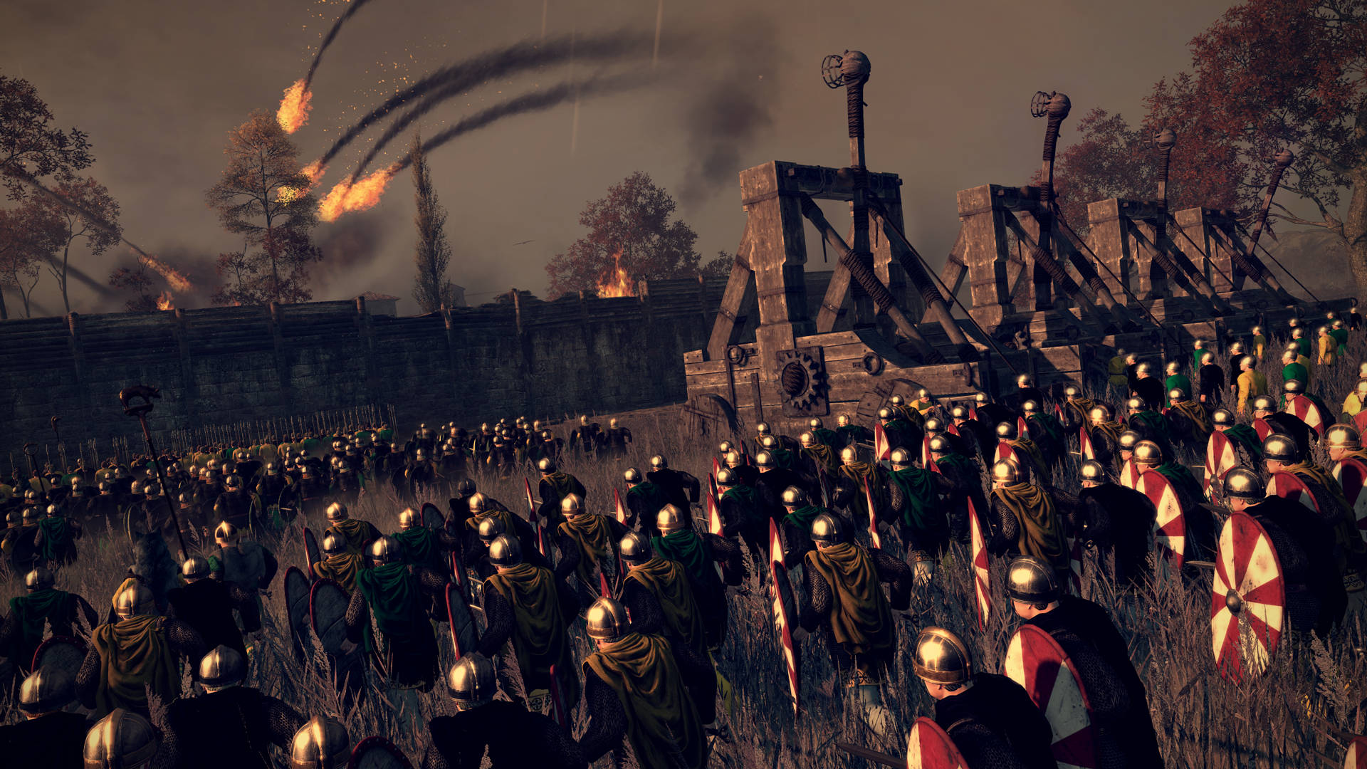 Total War：阿提拉 砲轟攻城 壁紙 — 一支龐大的中世紀士兵軍隊，手持盾牌和頭盔，在煙霧瀰漫的黃昏天空下向著燃燒的堡壘前進。