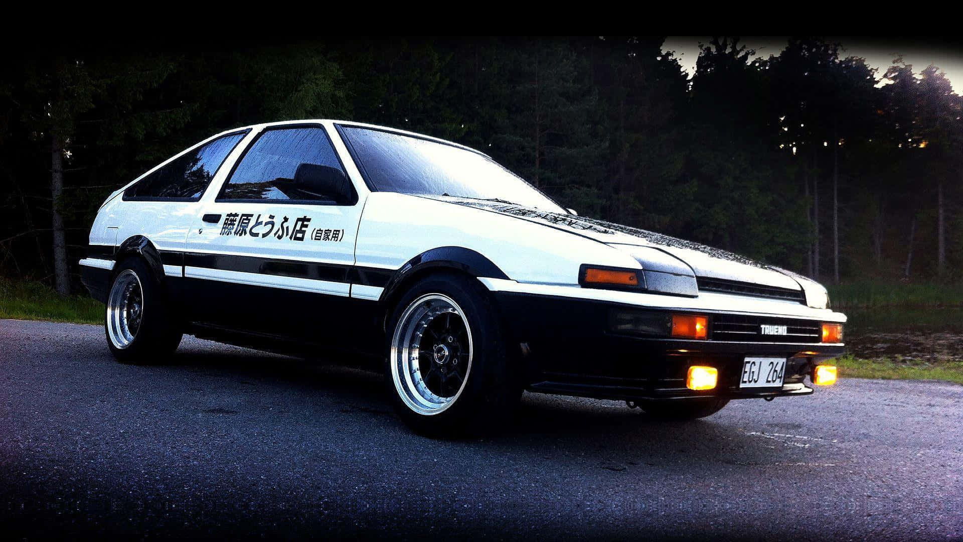 經典Toyota AE86於漂移賽道上飛馳 壁紙 — 一輛白色和黑色的豐田AE86跑車，帶有日文字，停泊在黃昏時分的黑暗道路上，背景有樹木。