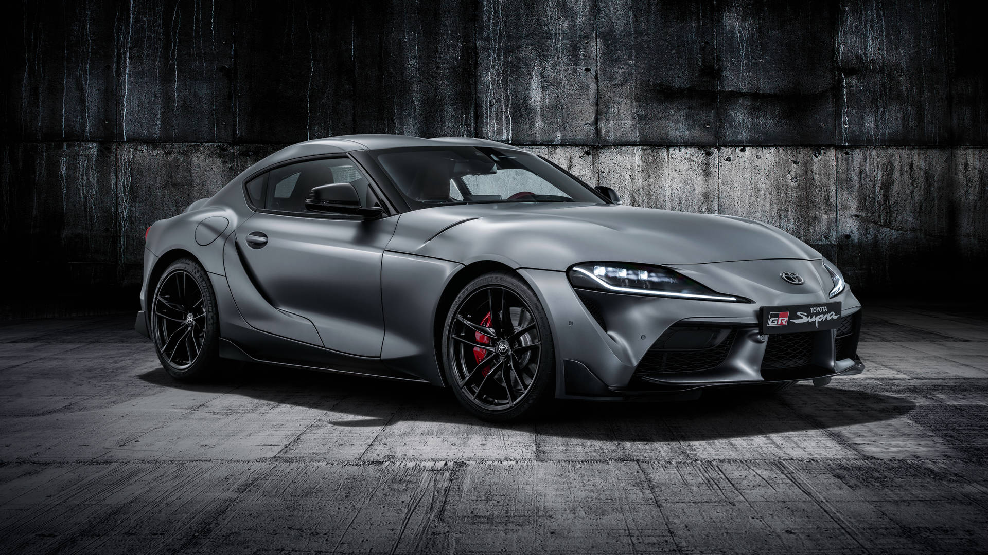 啞光灰色豐田GR Supra，紅色制動器，停在混凝土車庫中。