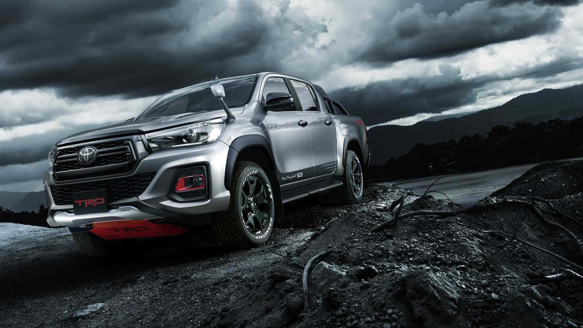 暴風雨天空下岩石地形上的銀色豐田 Hilux TRD 貨車