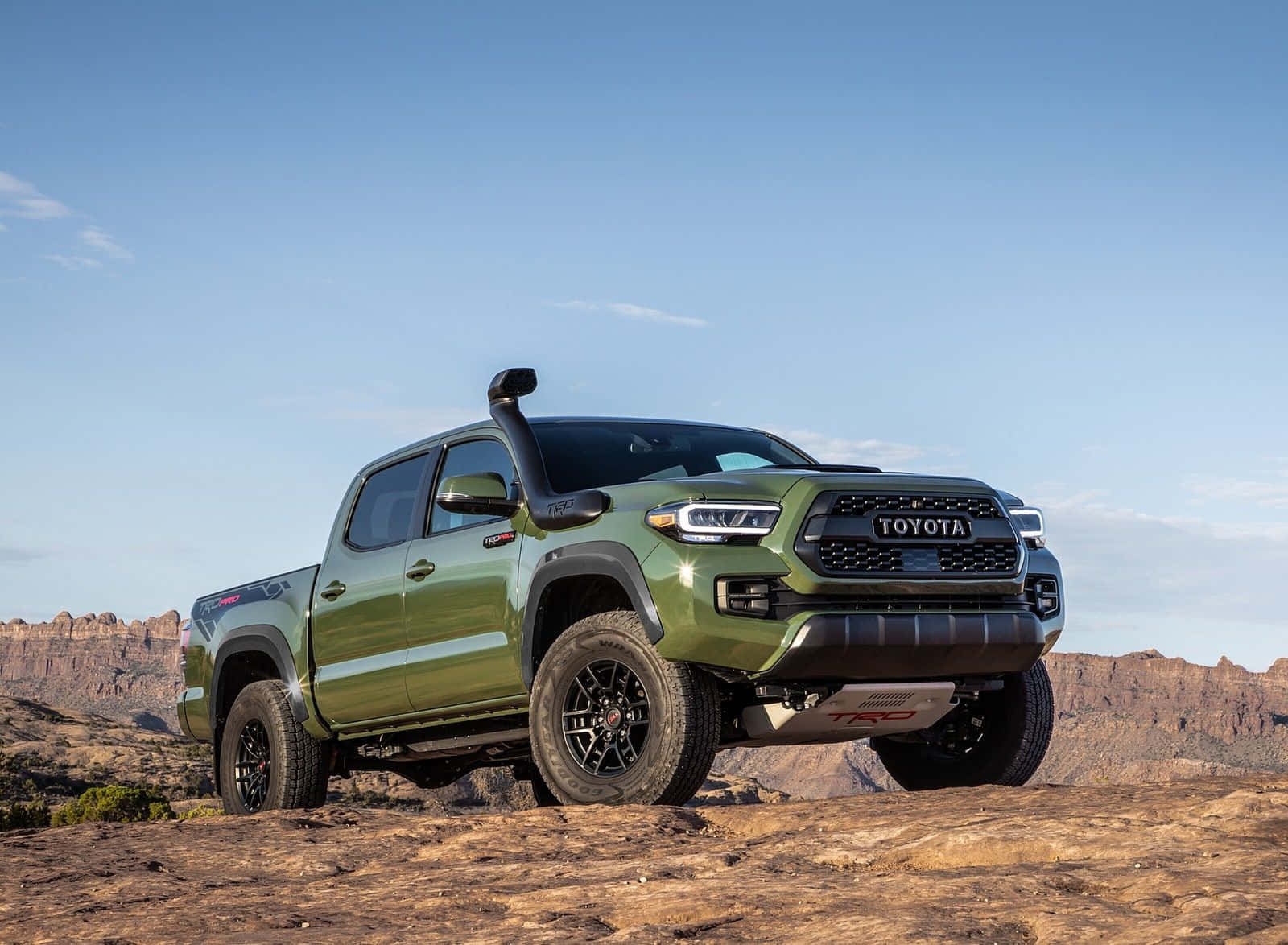 橄欖綠色的豐田Tacoma TRD Pro皮卡車在藍天下的岩石沙漠地形上。