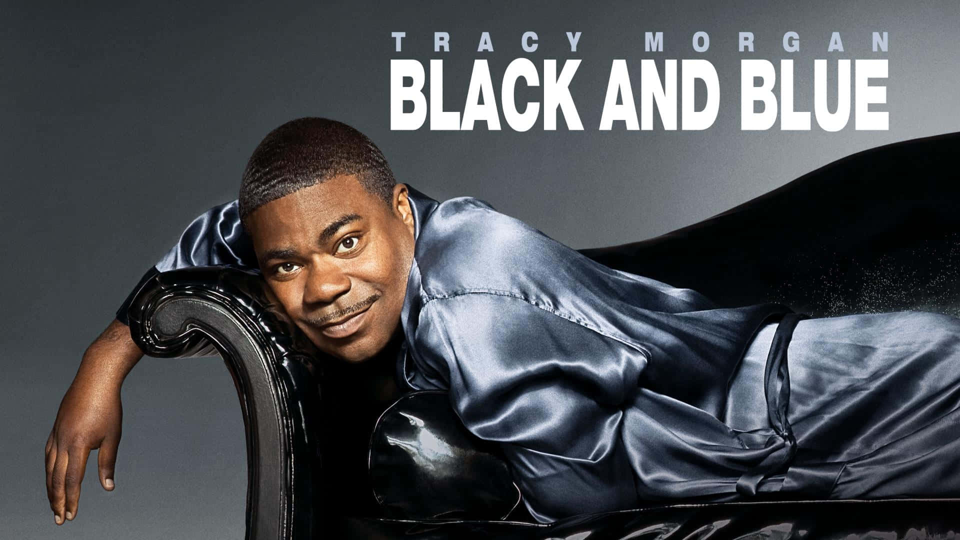 Tracy Morgan 桌布 壁紙 — Tracy Morgan 自信地穿著一件時尚的黑色緞面長袍，靠在一張華麗的椅子上，背景是柔和的灰色，上面有粗體白色文字。