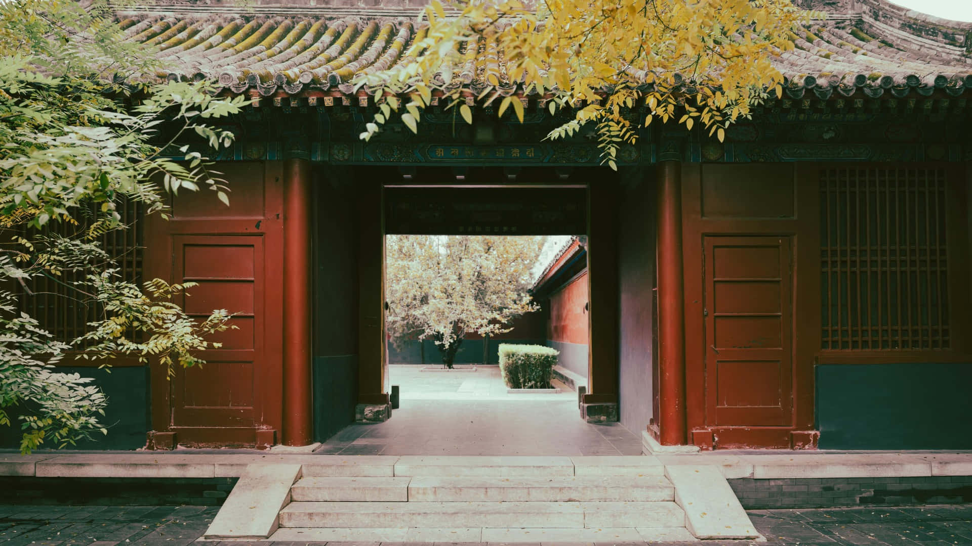  壁紙 — 傳統中式大門，紅色柱子與瓦片屋頂，被金色秋葉和向內延伸的石階環繞。