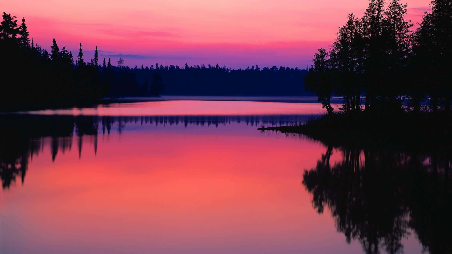 Sunset Landscape 桌布 壁紙 — 一個寧靜的湖泊映照出充滿活力的粉紅色和紫色日落天空，以深色樹木剪影為框。