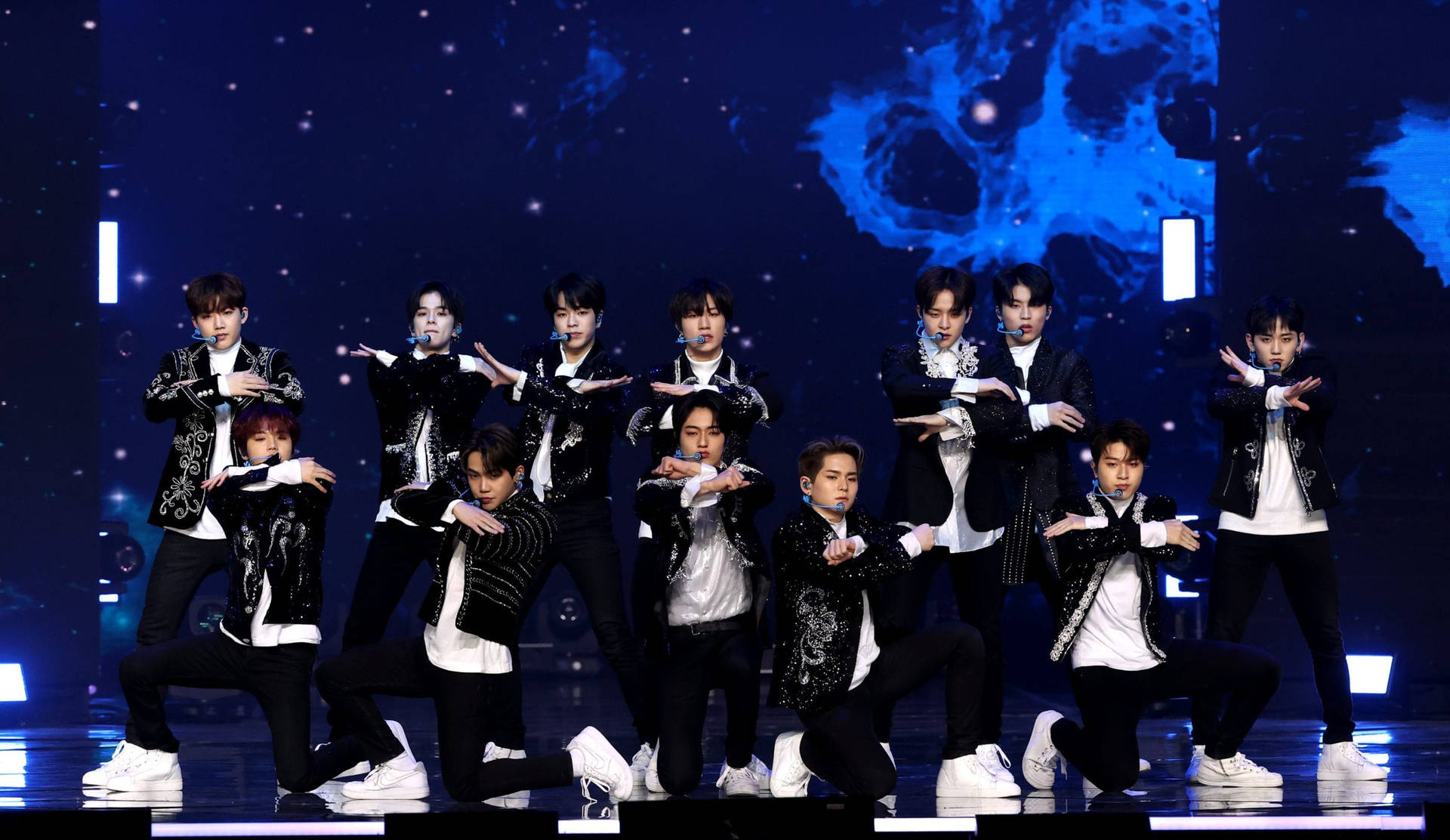K-pop團體穿著黑白服裝在星光舞台上跳舞。
