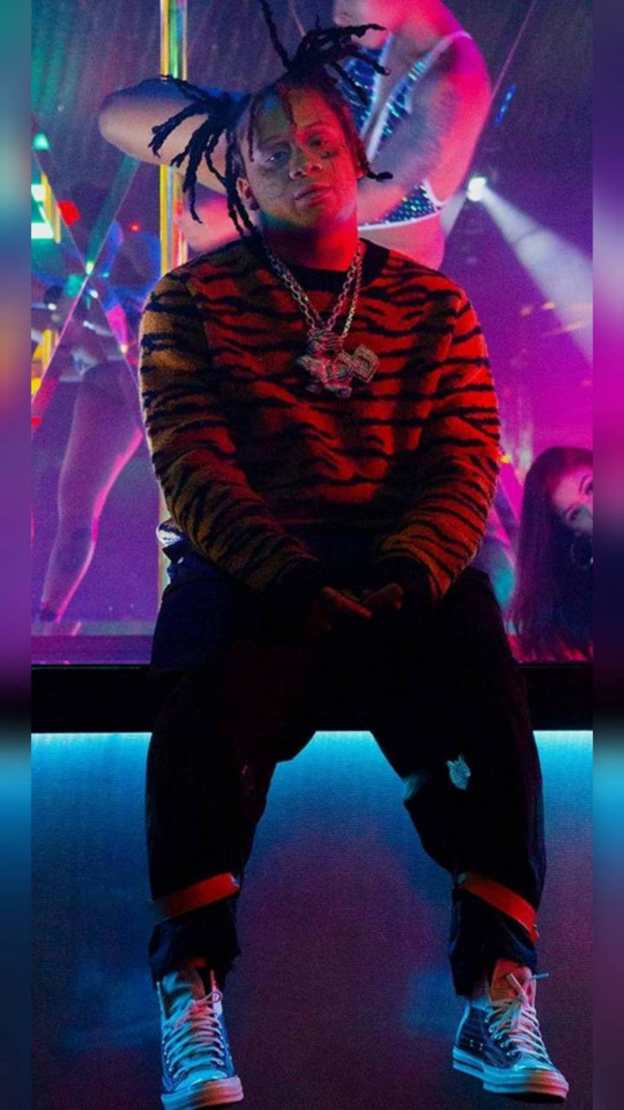Trippie Redd 老虎圖案毛衣 壁紙 — 一名留著辮子頭的男人自信地坐在霓虹燈俱樂部裡，穿著虎紋毛衣和厚底運動鞋。