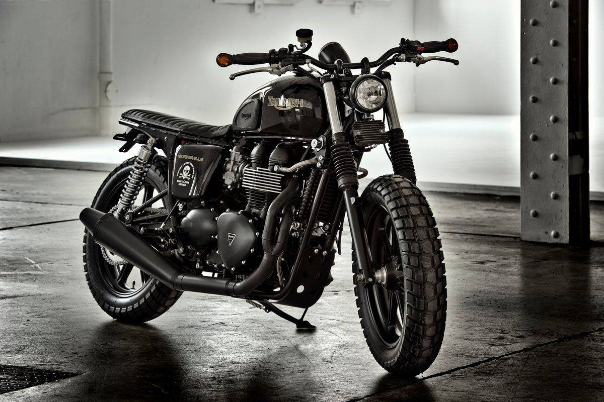 Triumph Bonneville Rocker T120 摩托車 壁紙 — 一架啞光黑色的 Triumph Bonneville Bobber 電單車矗立在一個簡樸的工業倉庫中，地面是混凝土，鋼樑用鉚釘固定。