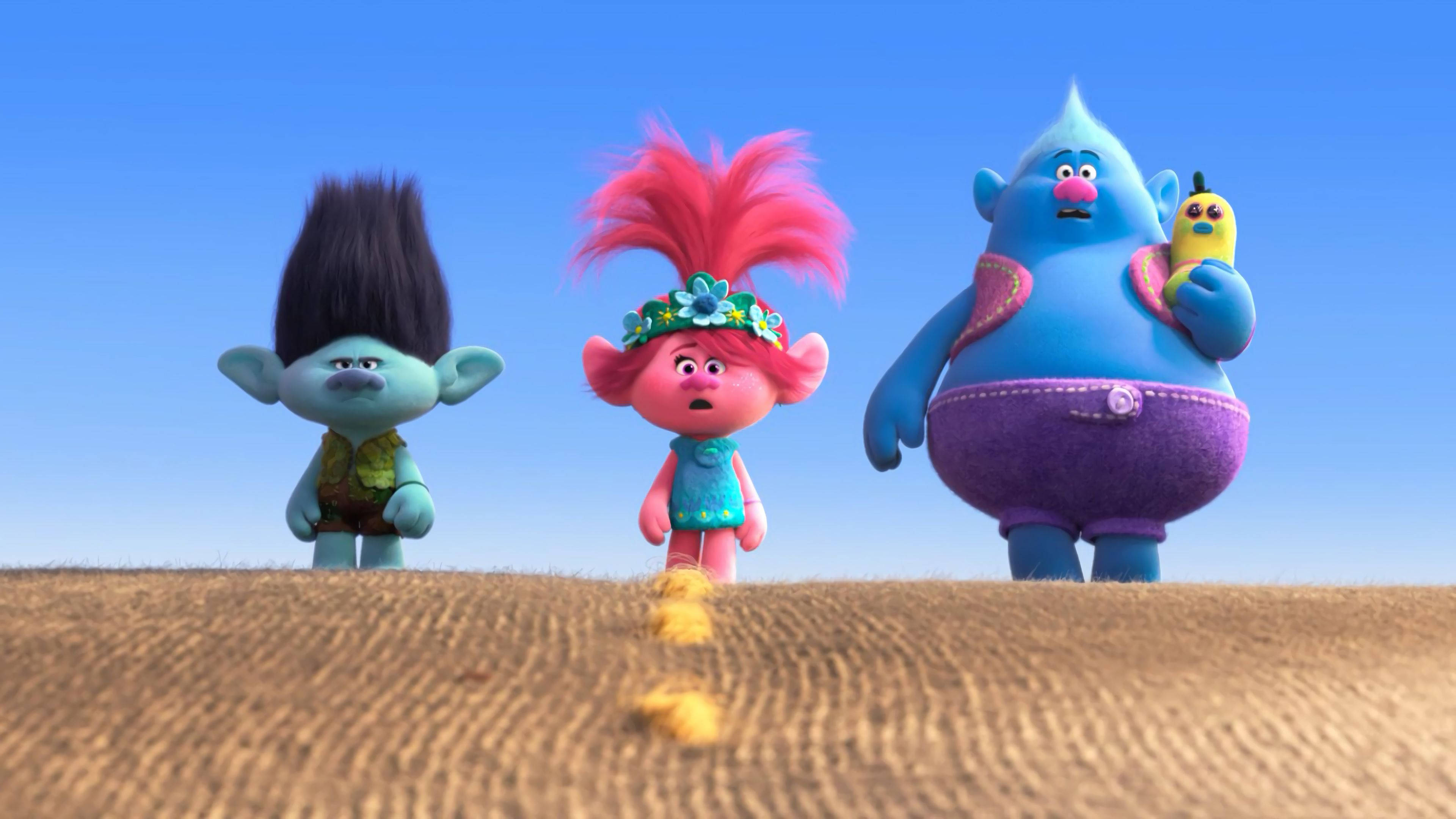Trolls Branch、Poppy與Biggie 壁紙 — 三個色彩繽紛的動畫巨魔站在沙丘上，天空清澈湛藍，其中一個拿著香蕉。