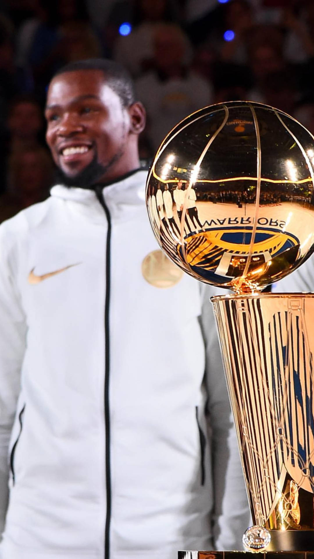 籃球運動員在場館內微笑站在NBA冠軍獎盃旁。