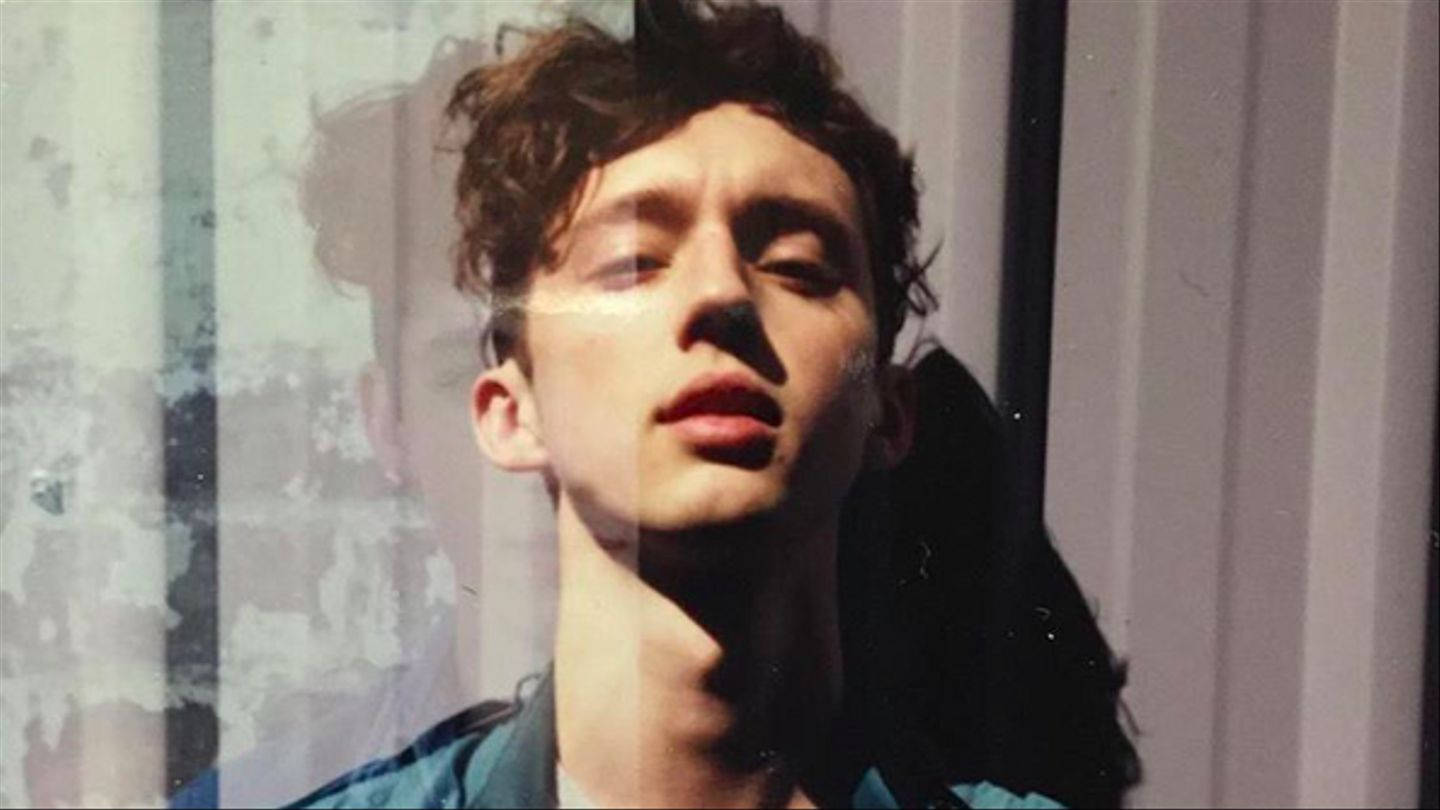 Troye Sivan《Cool Trilogy》專輯封面 壁紙 — 一個頭髮蓬鬆的年輕男子在柔和陽光透過破舊窗戶照射進來時向上凝視。