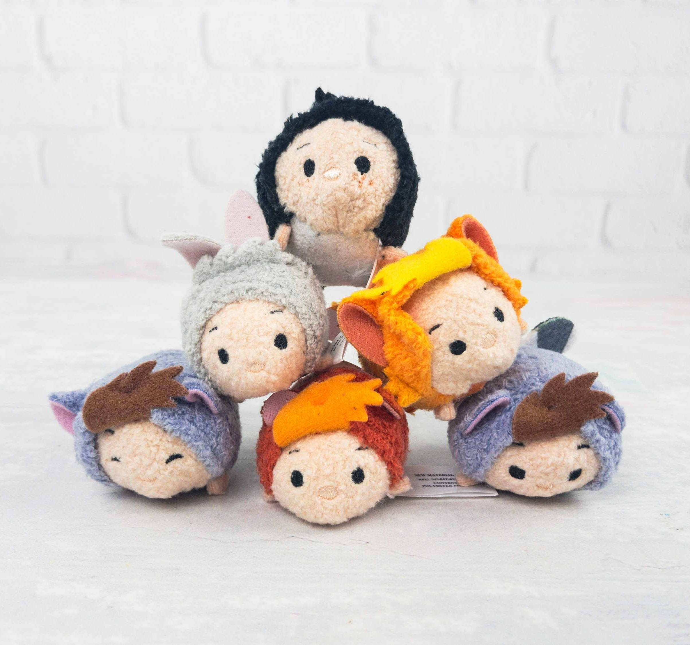 Tsum Tsum 彼得潘 壁紙 — 五個穿著色彩繽紛服裝的Tsum Tsum毛絨角色，在白色磚牆背景上排列成金字塔形狀。