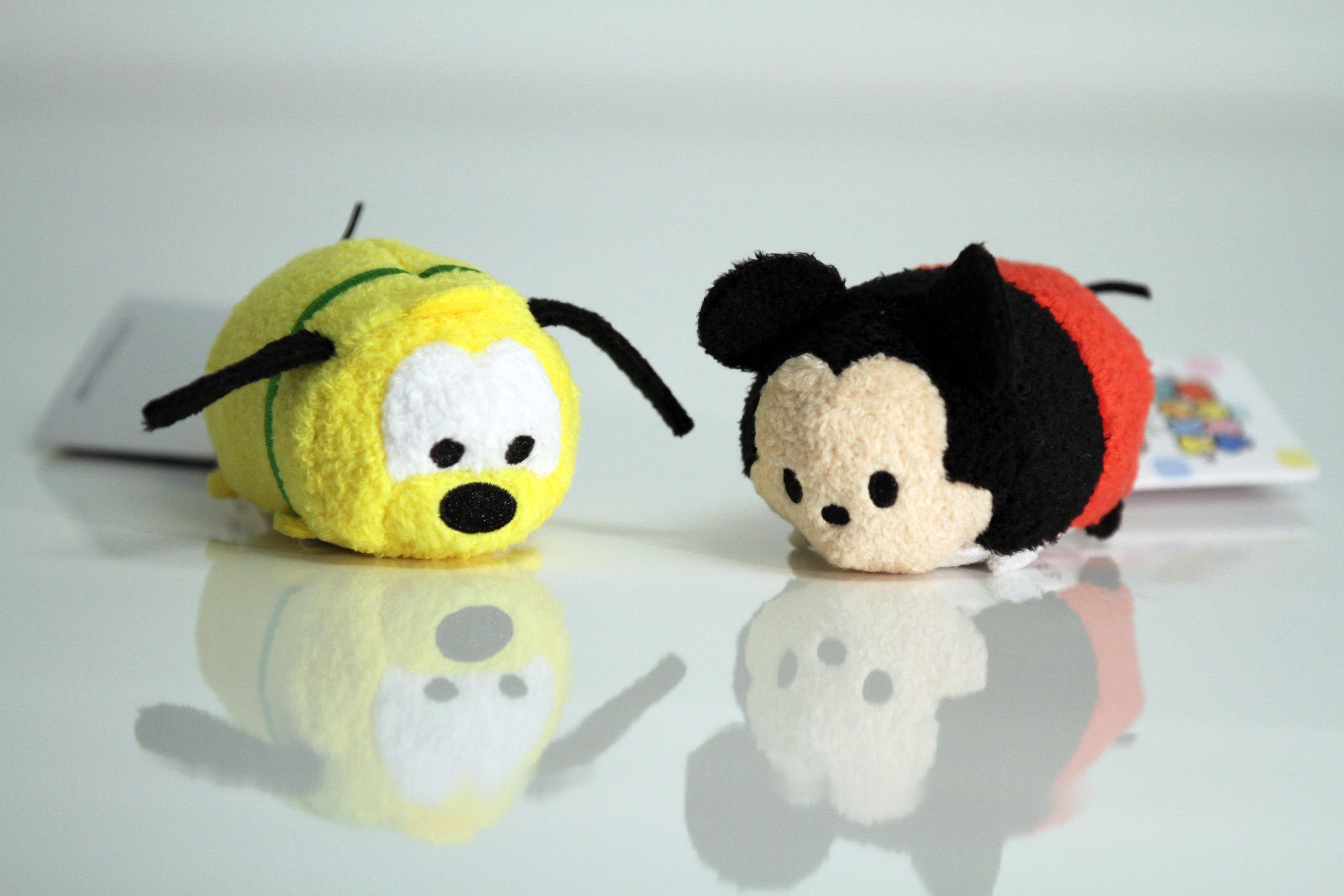 Tsum Tsum 米奇與普魯托 壁紙 — 兩個可愛的 Tsum Tsum 毛絨玩具米奇和布魯托並排坐在光滑的白色表面上，帶有清晰的倒影。