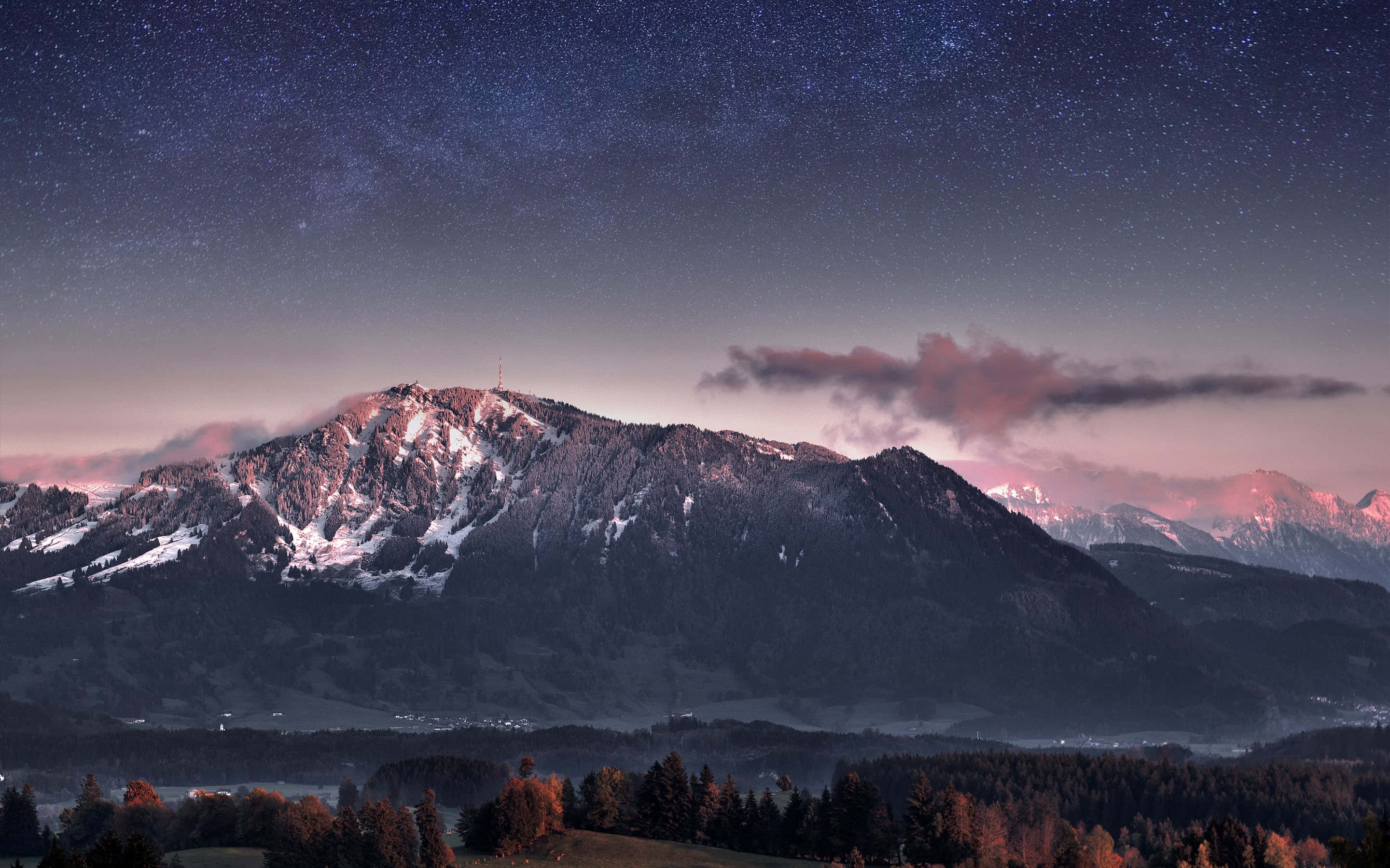美學星空山脈Tumblr筆電壁紙 壁紙 — 積雪的山峰在繁星點點的暮色天空下閃耀，粉紅色的雲朵和遠處的燈光在下方。