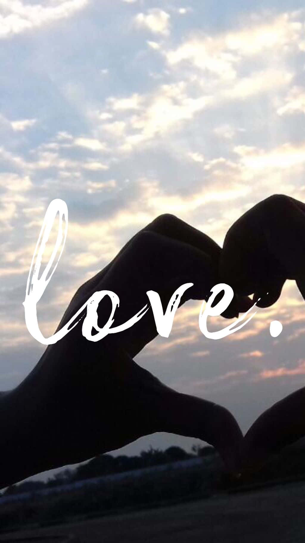 兩隻手在日落天空前形成一個心形，並以白色寫上 love。