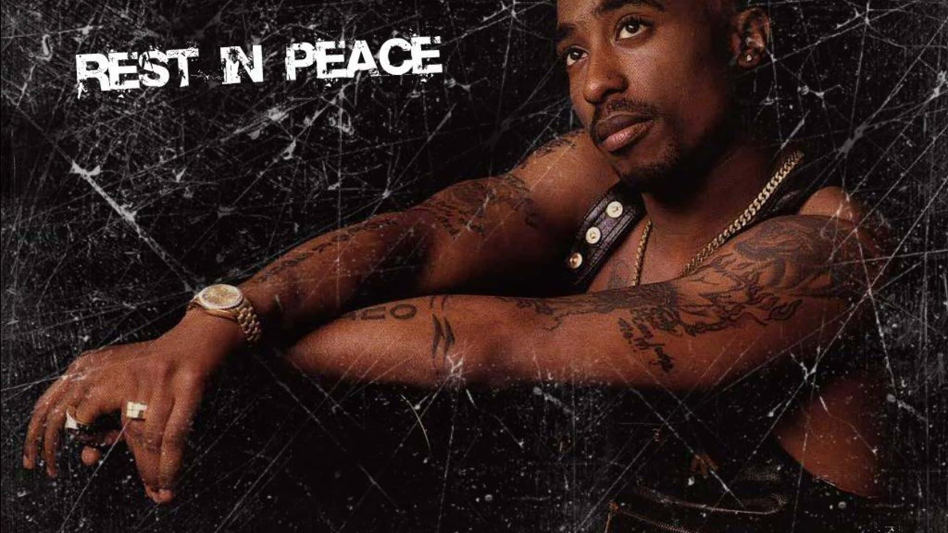 Tupac 桌布 壁紙 — Tupac Shakur 展示紋身手臂，背景為裂紋黑色，並帶有 'REST IN PEACE' 文字。