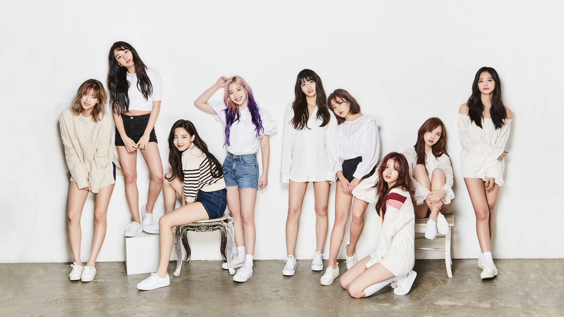 Twice 4K 穿著白色系服裝 壁紙 — 九位年輕女性穿著休閒白色服裝，在簡約工作室環境中自信地對著純白牆壁擺姿勢。