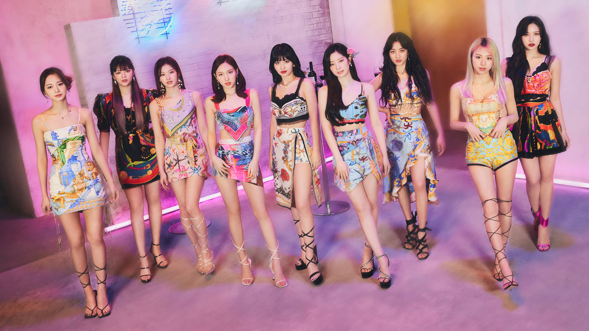 TWICE 4K 粉紅房間 壁紙 — 七位身穿鮮豔圖案服裝的女性在粉紅色霓虹燈下，於風格化的攝影棚中自信地擺出姿勢。