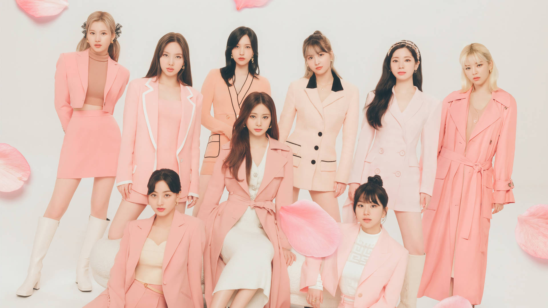 TWICE 4K 粉紅服裝 壁紙 — 七位身穿協調粉色服裝的女性在白色背景前自信地擺姿勢，周圍飄浮著粉色花瓣。