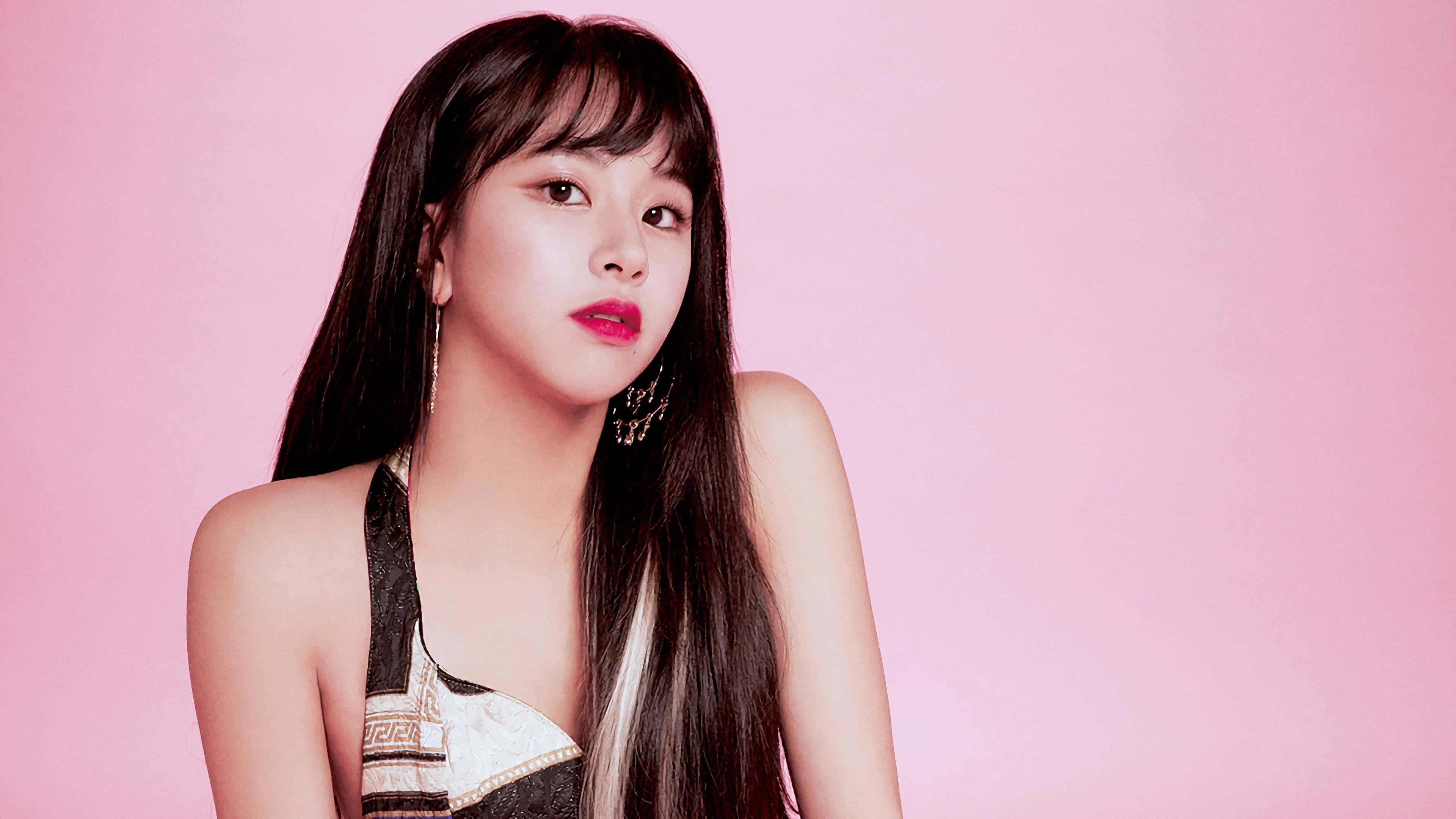 Twice 女子團體合照 壁紙 — 一位擁有長長黑髮和大膽紅唇的年輕女性在柔和的粉紅色工作室背景前擺姿勢。