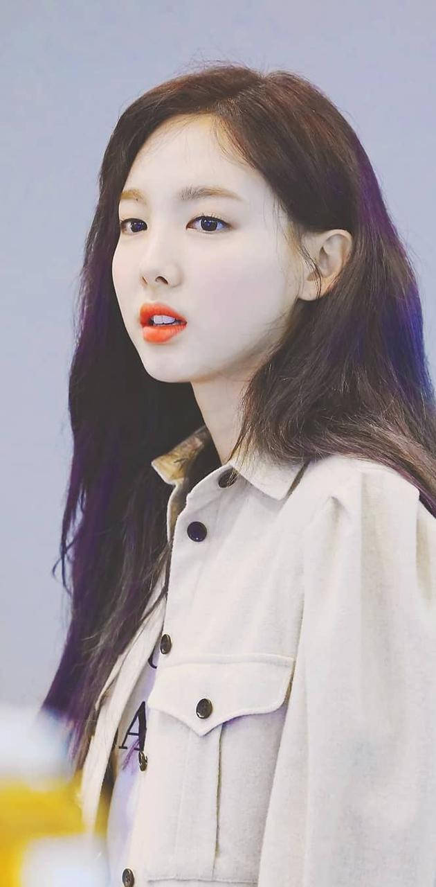 深色頭髮和橙色嘴唇的年輕女性穿著米色外套。