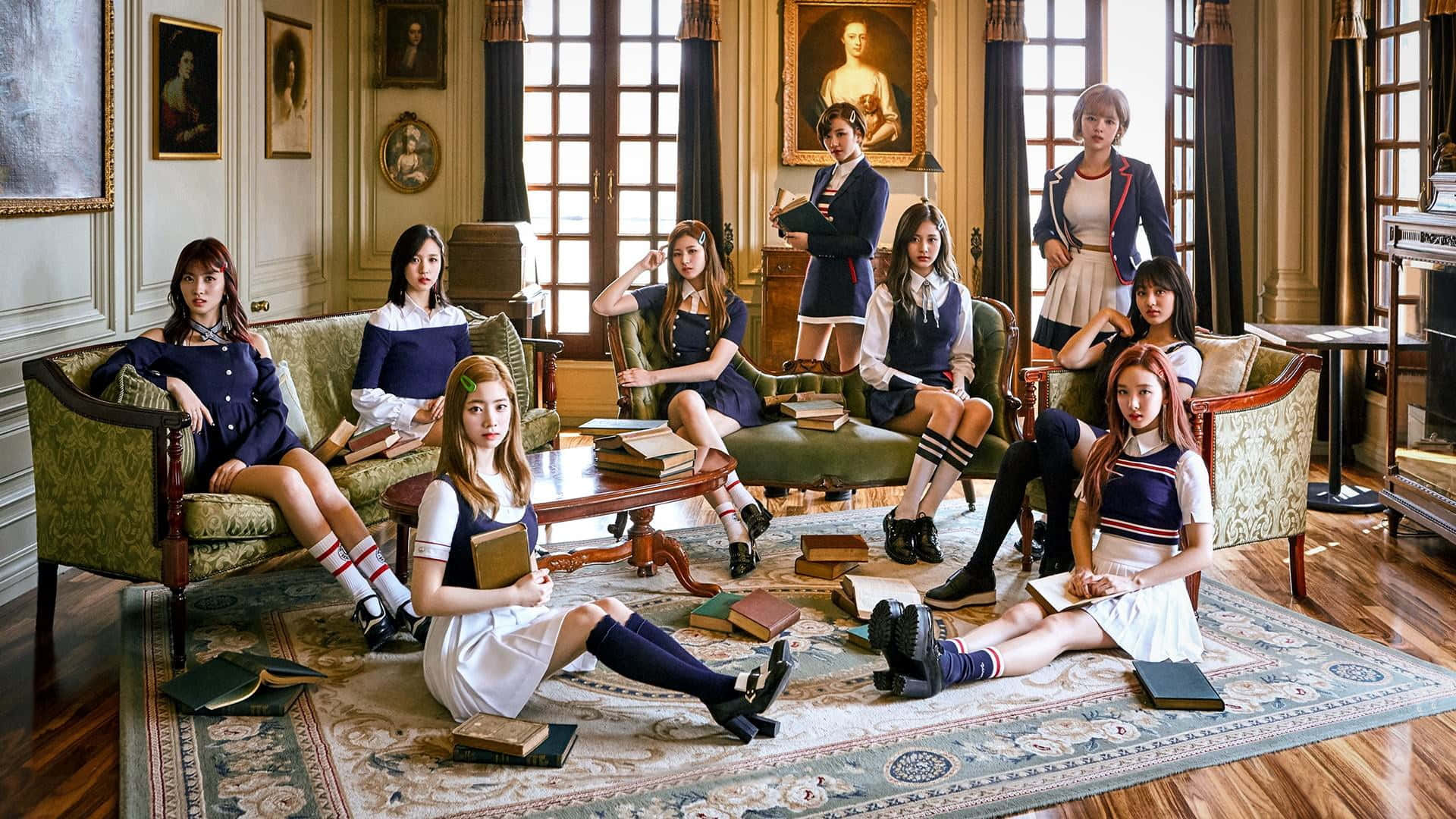 Twice - 絕美團體照 壁紙 — 七位身穿復古校服的年輕女性在一個充滿書籍和古董家具的宏偉、陽光充足的圖書館中優雅地擺姿勢。