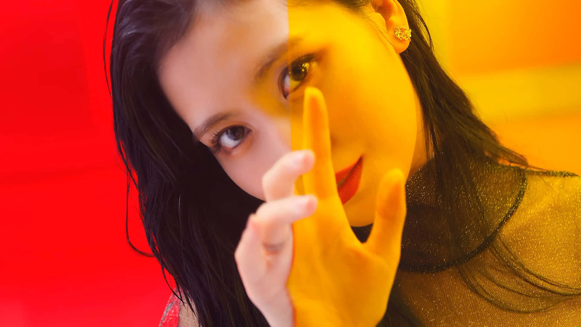 TWICE在歡樂多彩環境中合影 壁紙 — 一位深色頭髮、紅唇的女性，在紅黃分半的背景前，將手靠近臉部擺姿勢。
