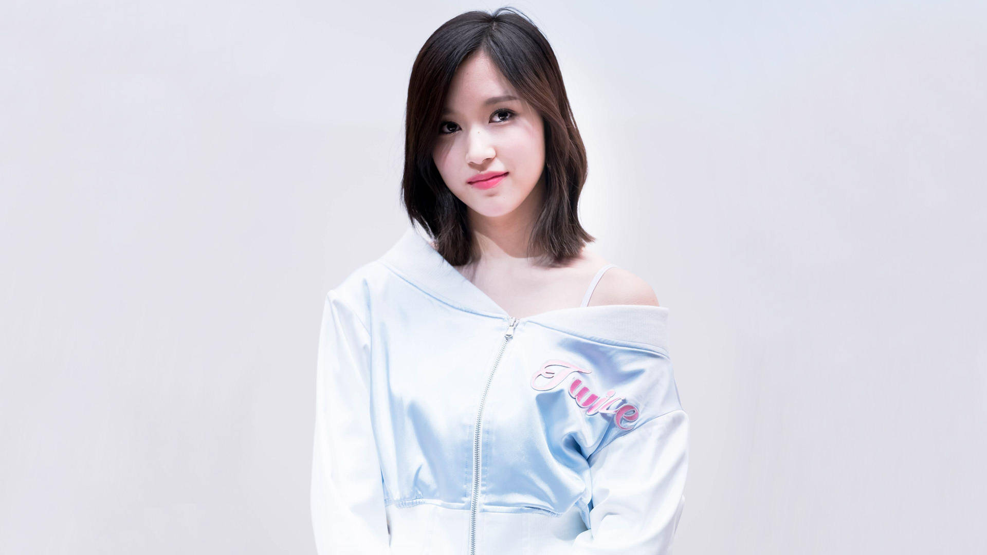 年輕女性穿著淺藍色連帽衛衣在攝影棚對著鏡頭微笑