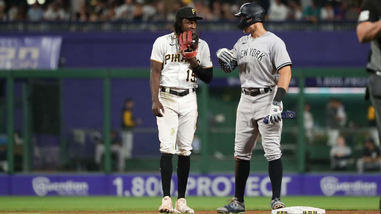  壁紙 — 兩名身穿球衣的棒球運動員站在球場上，一人穿着「Pirates」，另一人穿着「New York」，在球場燈光下進行比賽。
