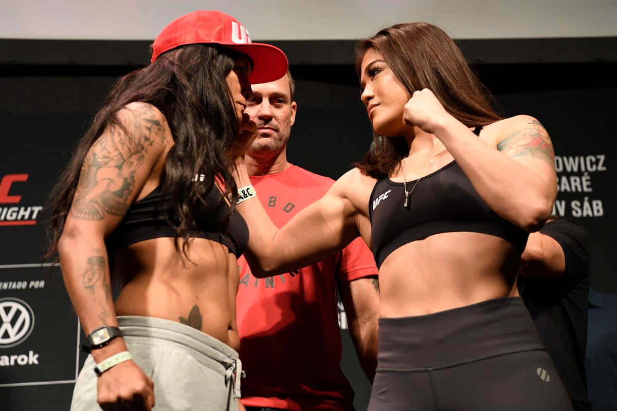  壁紙 — 兩名女性UFC拳手在稱重活動中，在裁判之間進行緊張的賽前對峙。