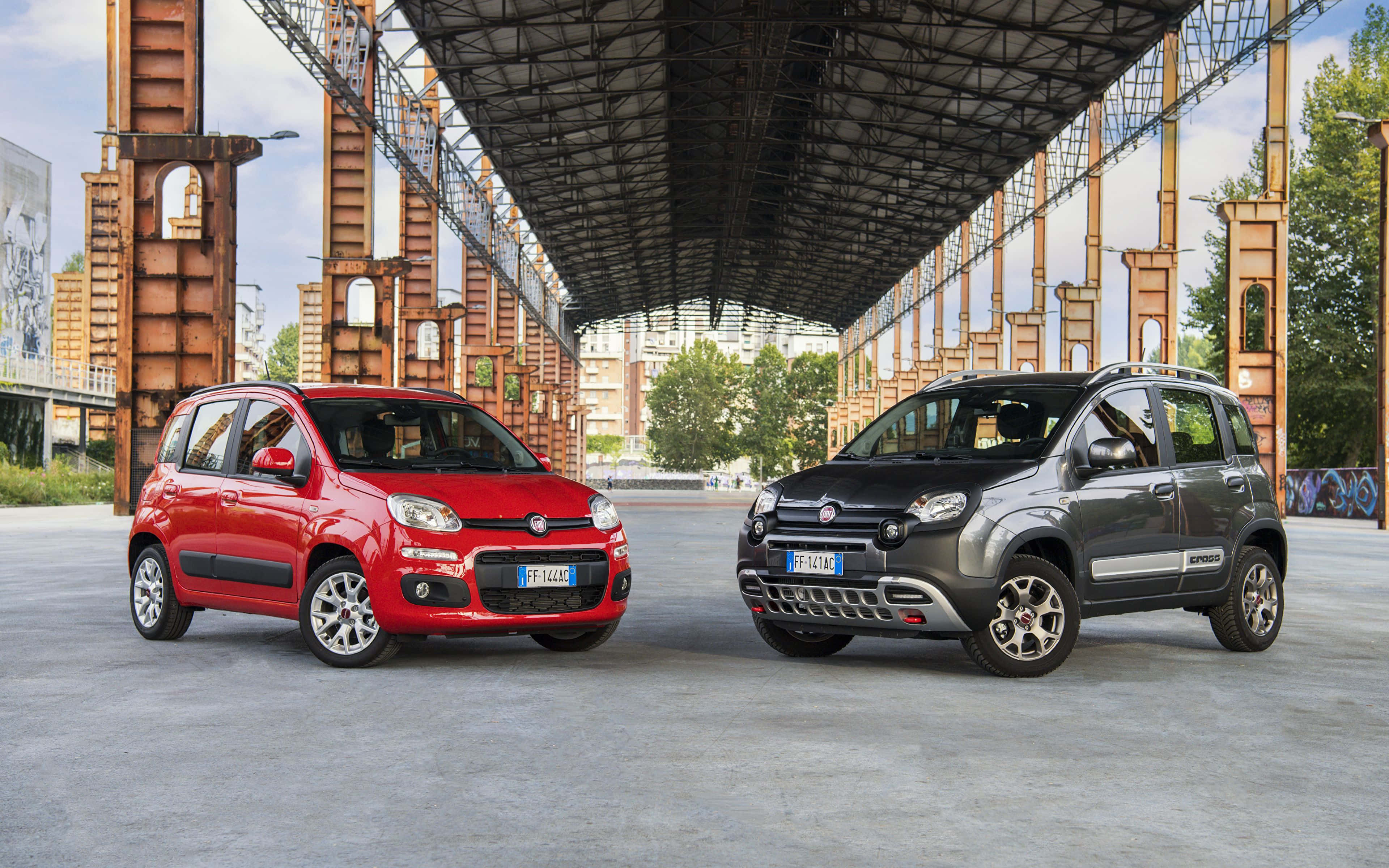 Fiat 500l 桌布 壁紙 — 兩輛紅色和灰色的Fiat Panda汽車停放在生鏽的工業鋼結構下，背景有塗鴉和綠色植物。