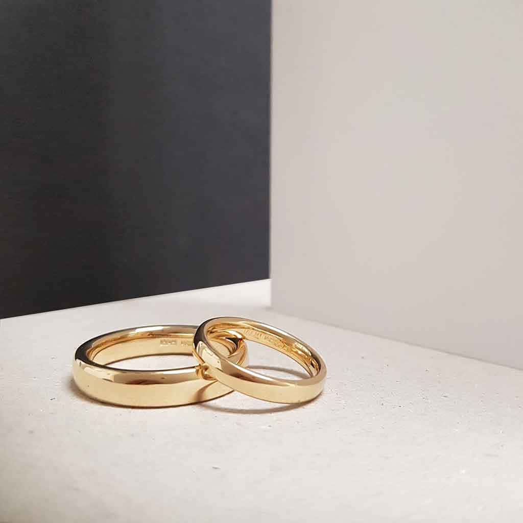 兩枚金色結婚戒指交織在白色表面上，黑白背景。