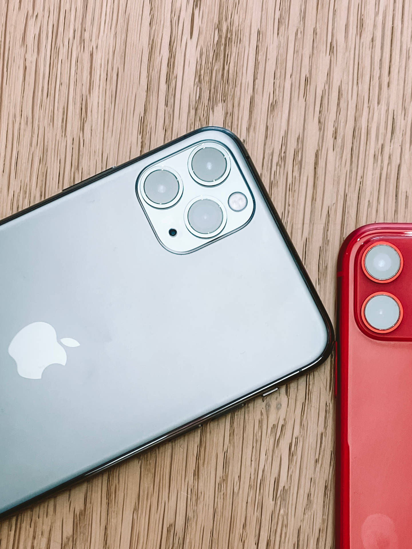 木質表面上的兩部銀色和紅色Apple iPhone