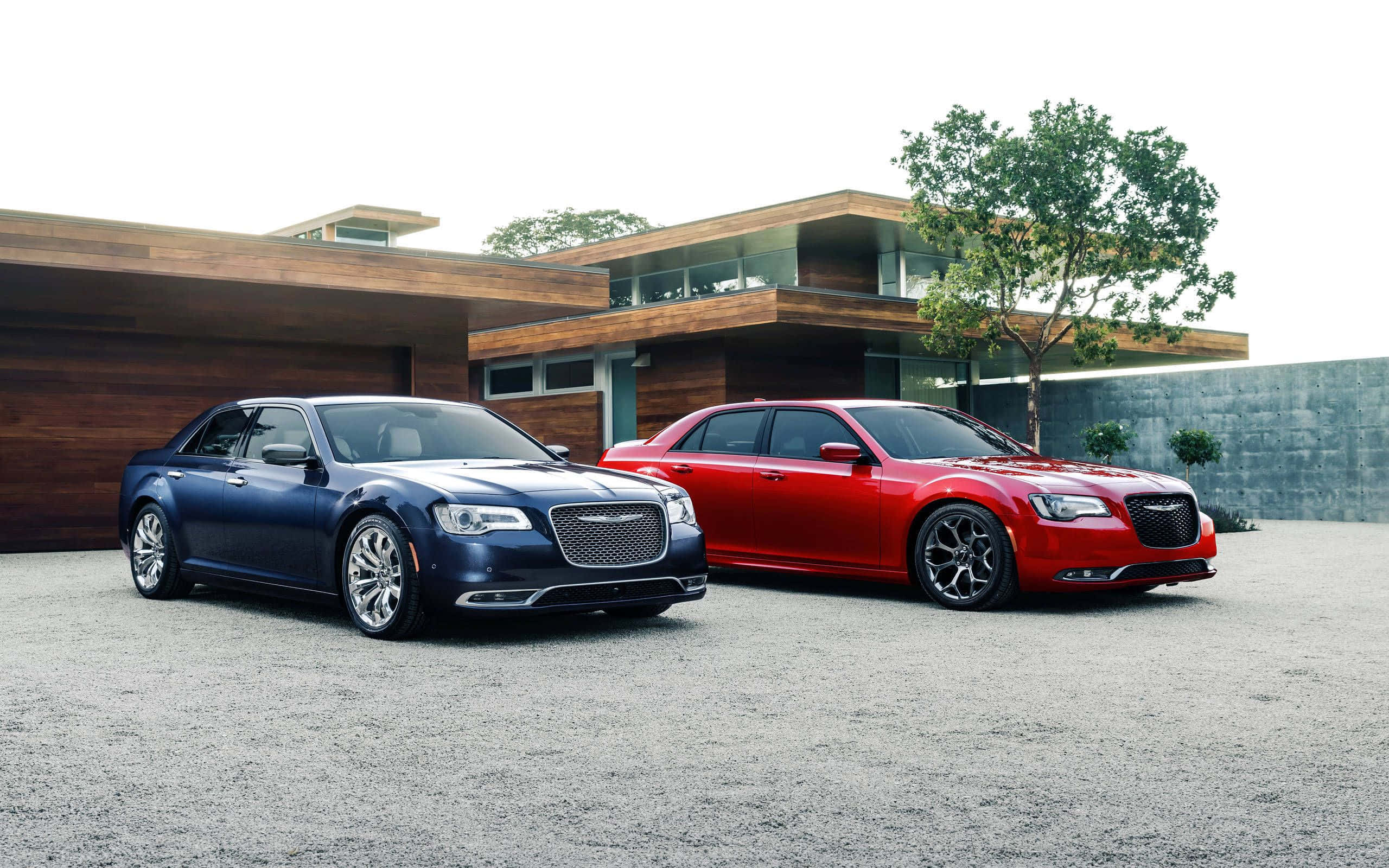 Chrysler 300 桌布 壁紙 — 兩輛豪華轎車，一藍一紅，停泊在現代木屋前的礫石上，木屋設有玻璃陽台。
