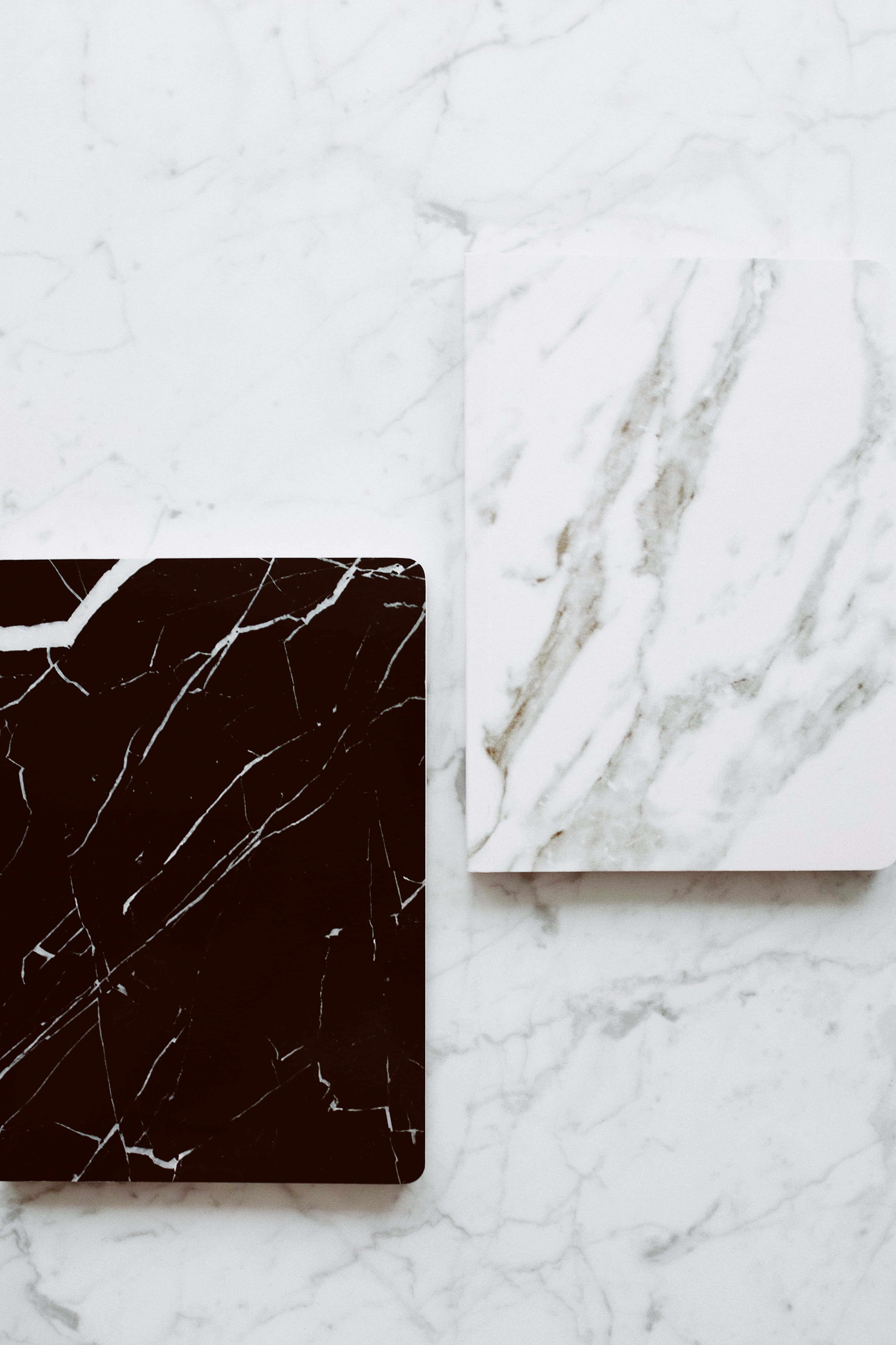 Black And White Marble 桌布 壁紙 — 兩塊黑白紋理大理石瓷磚以極簡平鋪方式放置於白色大理石表面上。
