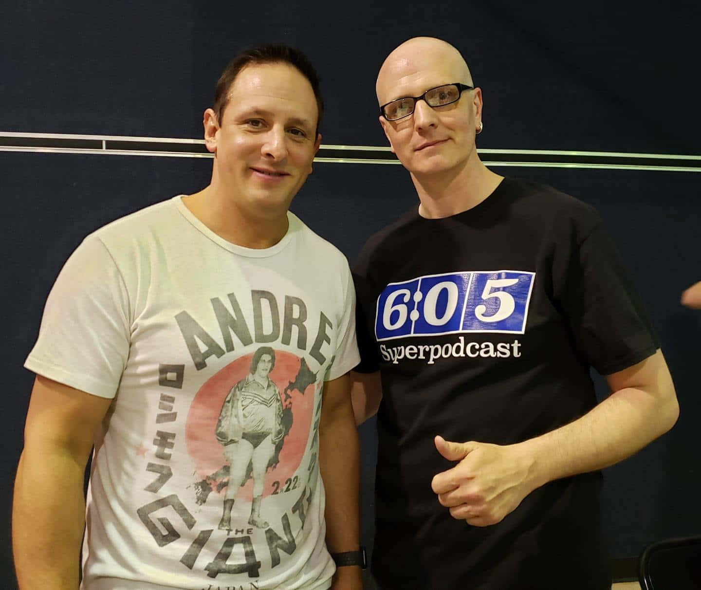  壁紙 — 兩個男人在黑暗背景下拍照，一個穿著Andre the Giant T恤，另一個穿著605 Superpodcast襯衫。