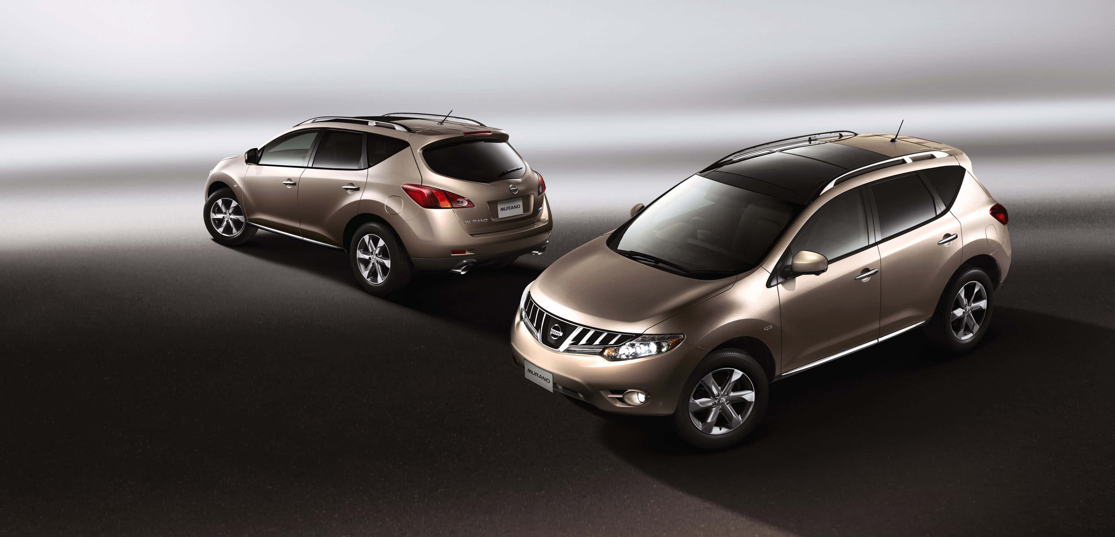 Nissan Murano 桌布 壁紙 — 兩輛金屬金色日產Murano SUV以角度放置在深色工作室地板上，帶有柔和漸變燈光。