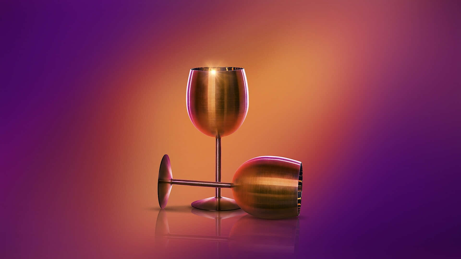  壁紙 — 兩個金屬酒杯，一個直立，一個倒下，在漸變紫橙色背景上投射出閃爍的反光。