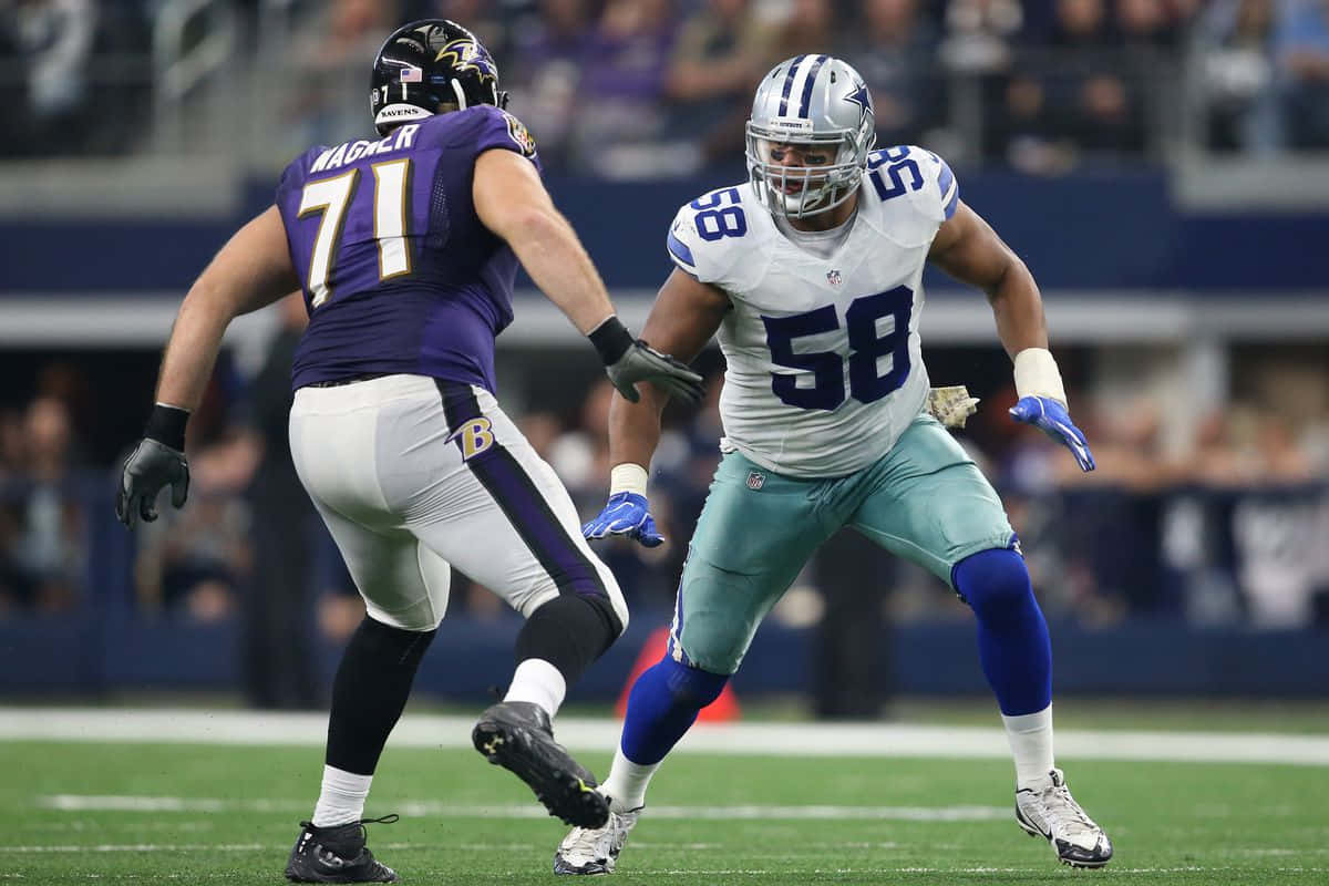  壁紙 — 兩名身穿紫色和白色球衣的NFL球員在球場燈光下於綠色場地上激烈競爭。