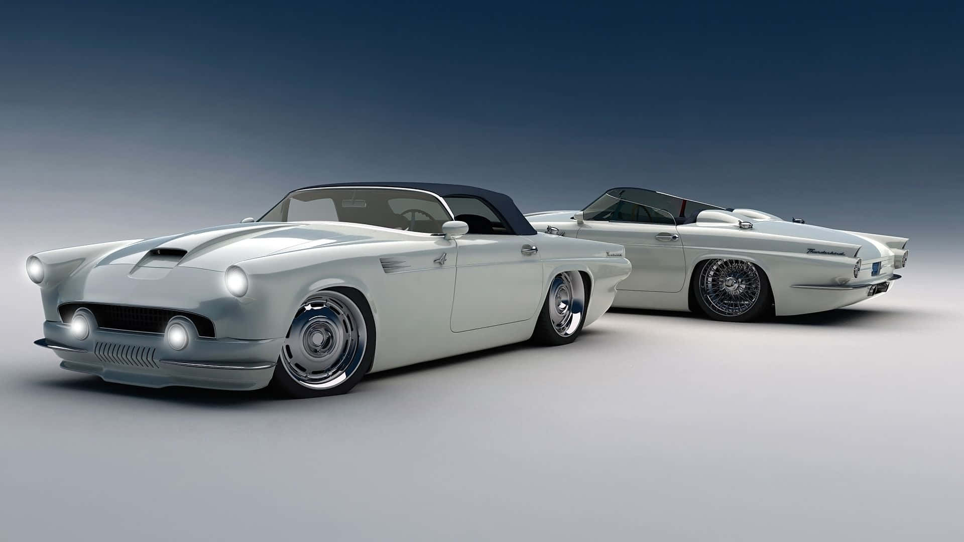 Ford Thunderbird 桌布 壁紙 — 兩輛時尚的銀色定制敞篷車，配備黑色頂篷和鍍鉻輪圈，在漸變藍灰色工作室背景前擺姿勢。