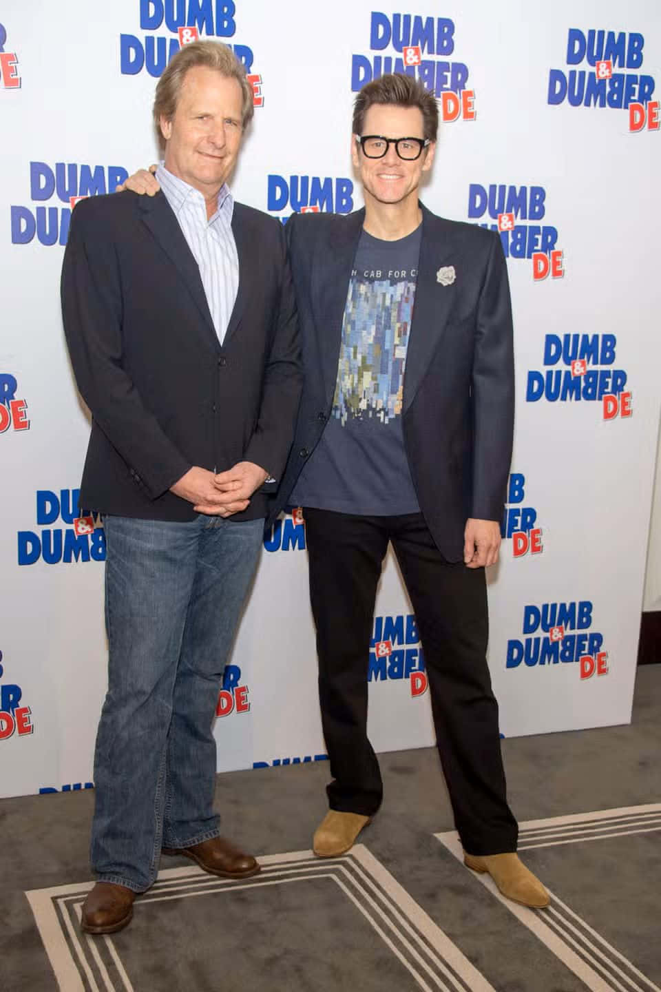  壁紙 — 兩位微笑的男士在《Dumb and Dumber To》電影首映禮上，於品牌背景前一起擺姿勢。