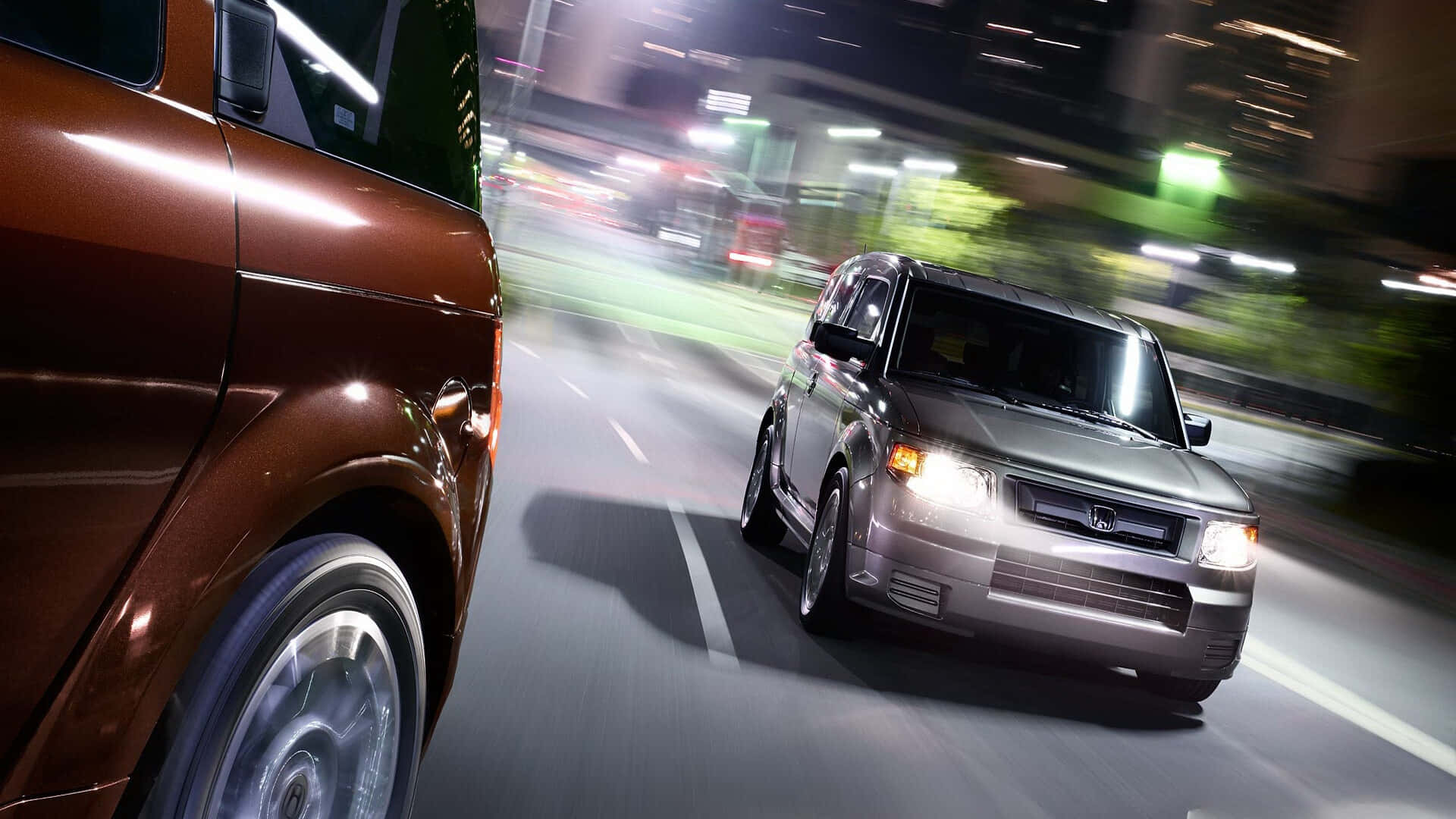 Honda Element 桌布 壁紙 — 兩輛SUV在夜晚霓虹燈閃爍的城市街道上奔馳，帶有動態模糊的條紋。