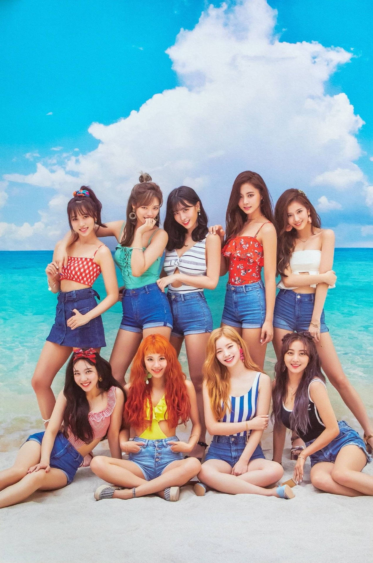 九位穿著夏季服裝的年輕女性在陽光明媚的海灘上快樂地擺姿勢。