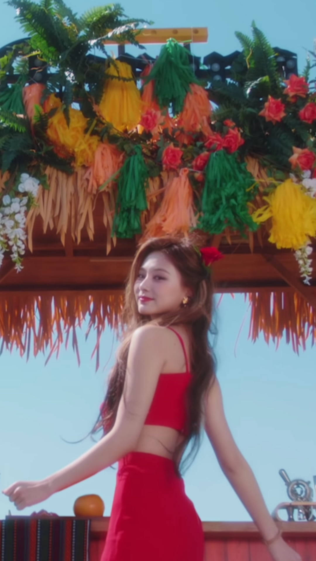 紅裙女性在熱帶茅草屋頂下與花朵