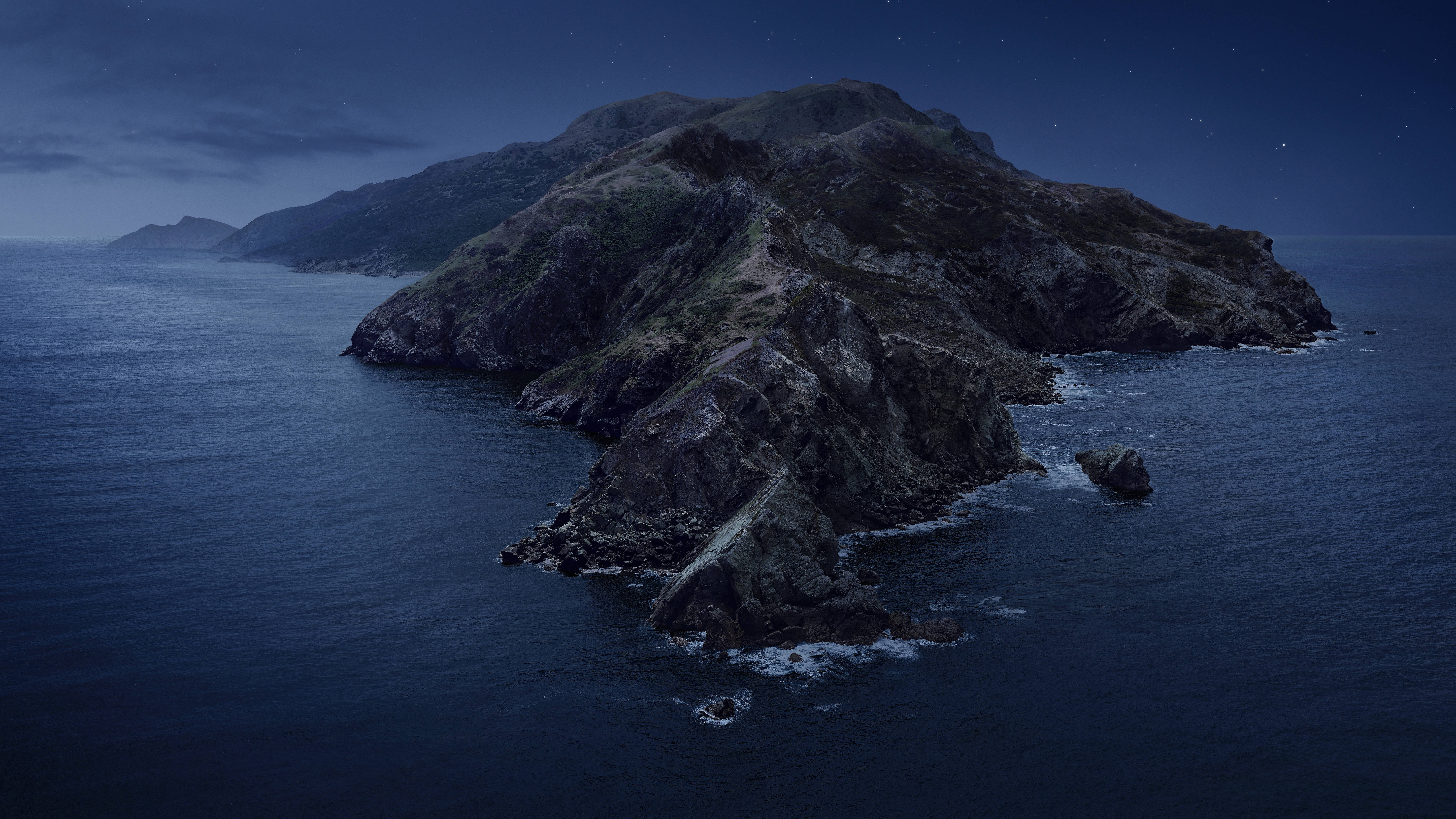 T形島嶼 macOS 壁紙 — 一座崎嶇的岩石島嶼從深藍色的海洋中升起，在繁星點點的夜空下，溫柔的海浪拍打著懸崖。