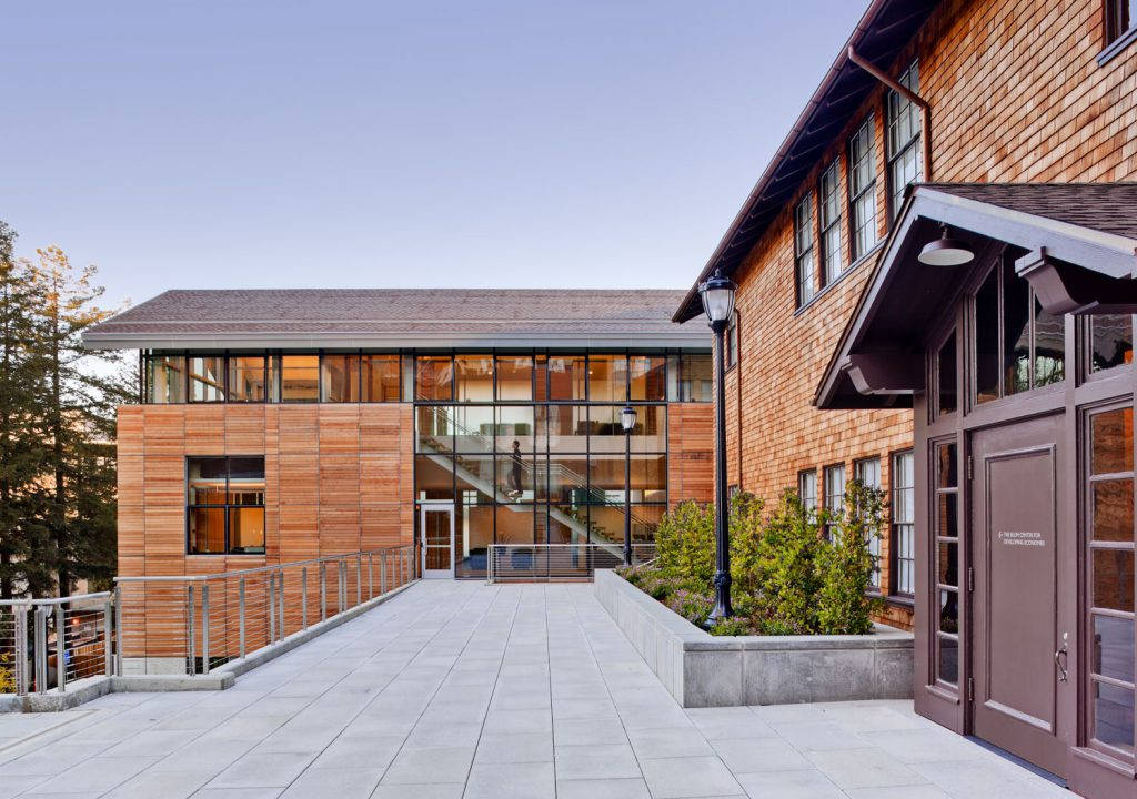 UCB標誌性布羅姆大樓：學習與創新的燈塔 壁紙 — 現代木質玻璃建築，寬闊石徑通往玻璃圍封樓梯，晴空萬里。