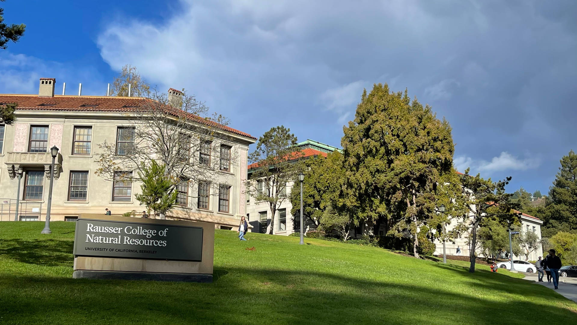 Rausser College of Natural Resources 標誌，學生在長滿草的大學山坡上行走。