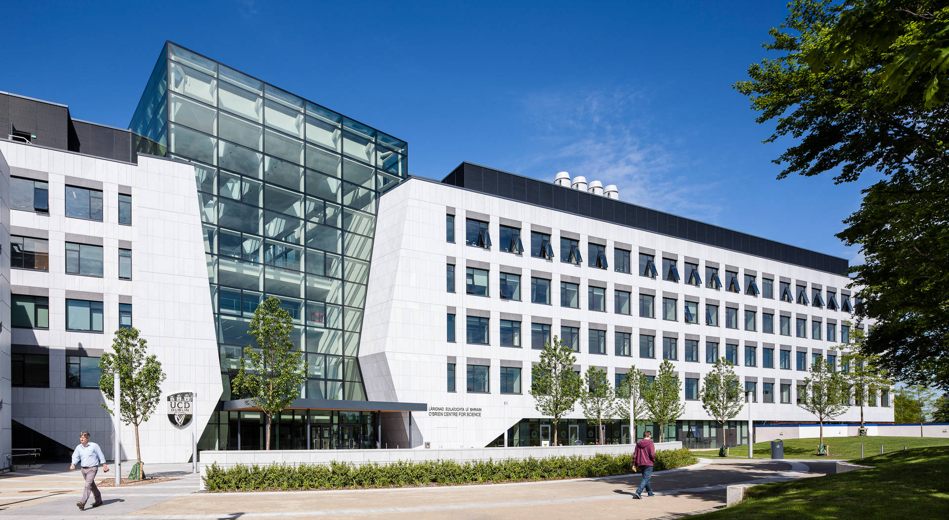 現代大學建築，玻璃外牆，人們在校園小路上行走。