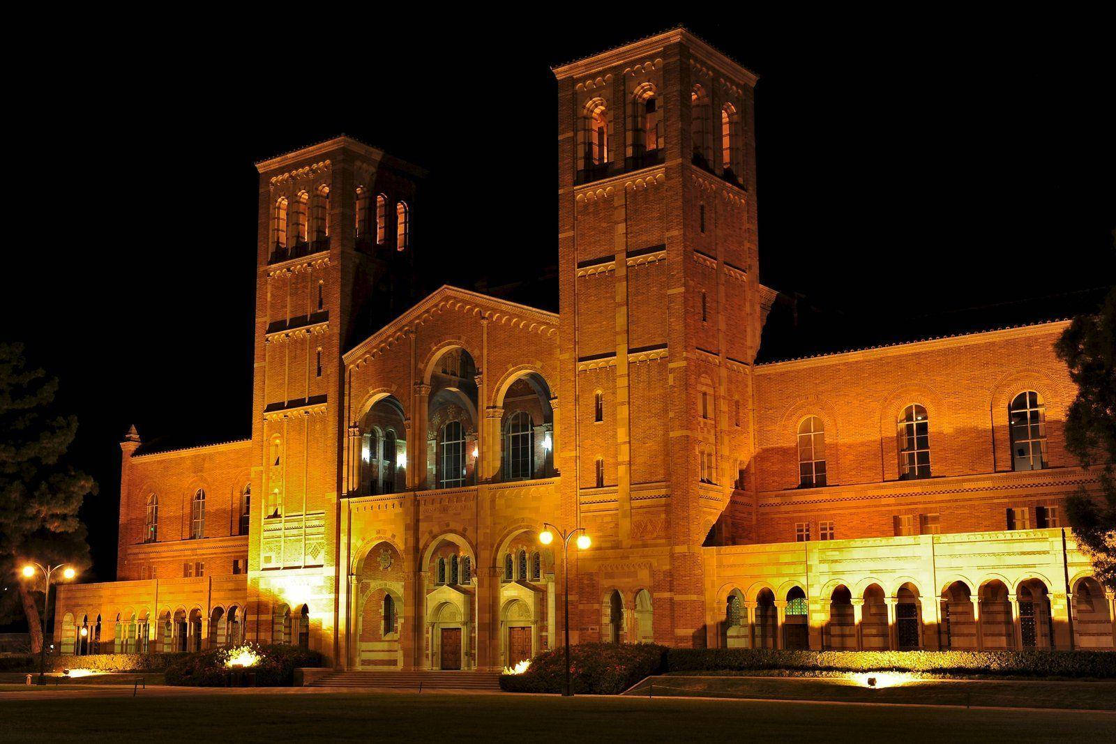 夜間亮燈的宏偉磚造大學建築，帶有拱形窗戶和塔樓。