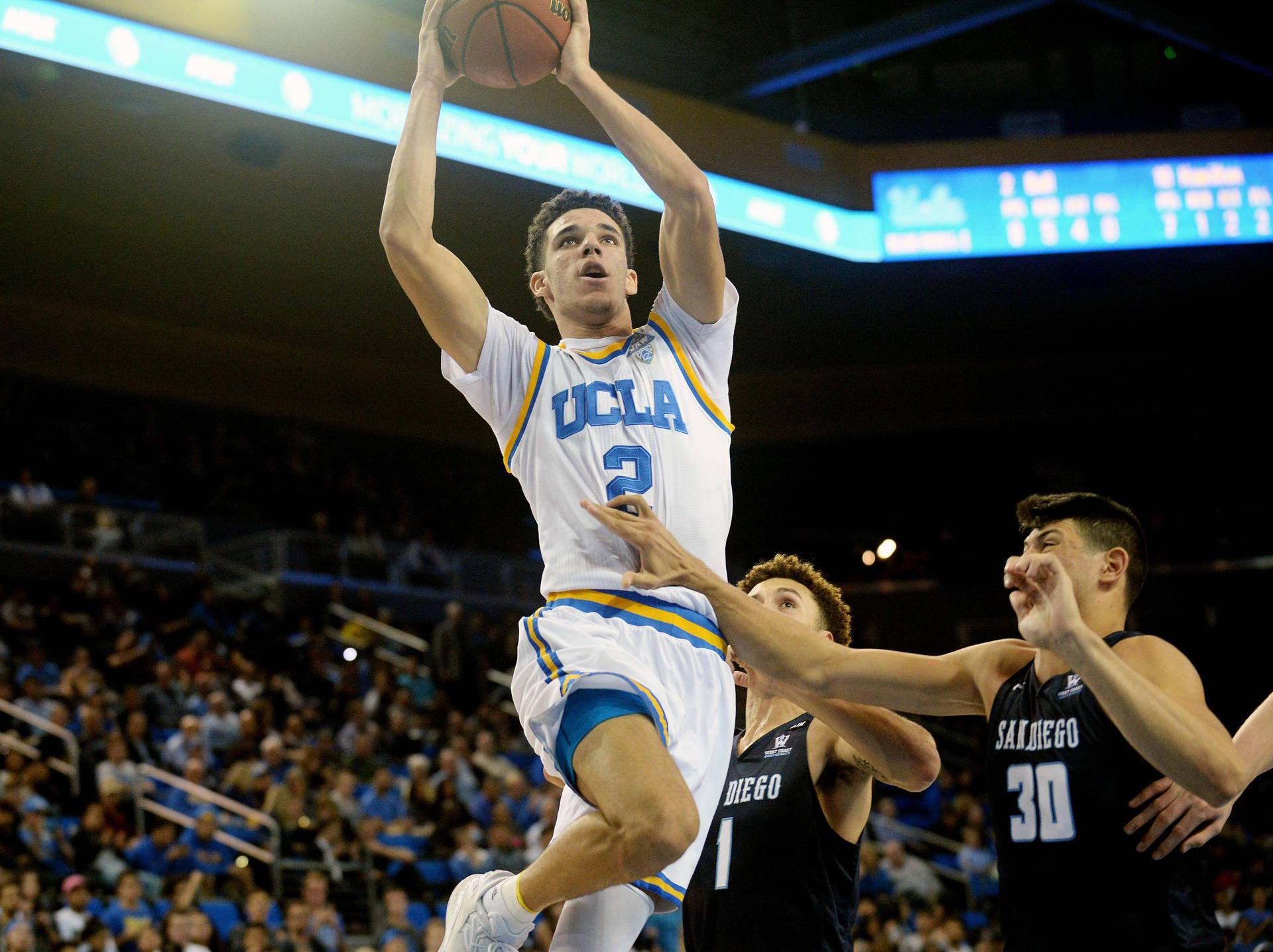 UCLA 隆佐·巴爾灌籃 壁紙 — 一名UCLA籃球運動員在明亮的場館燈光下高高躍起投籃，防守球員逼近。