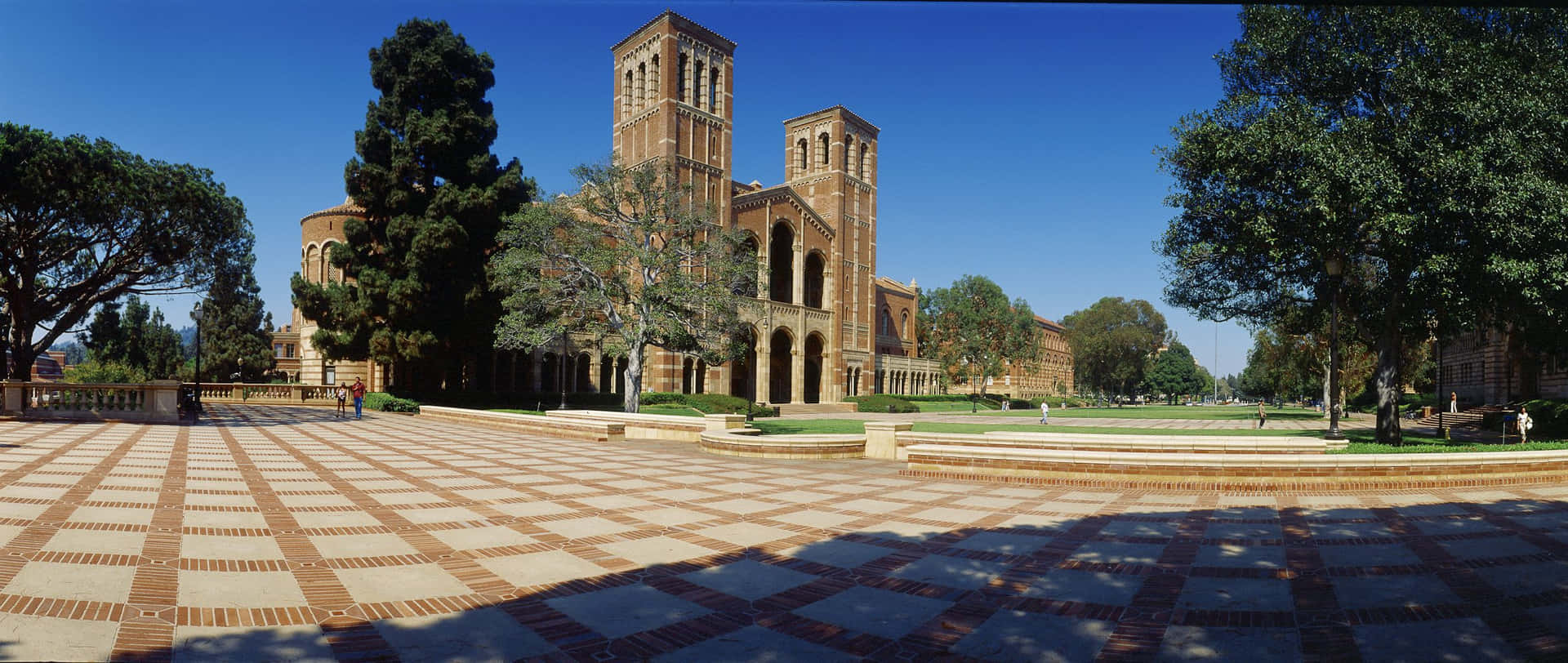 陽光明媚的大學庭院，設有棋盤格磚廣場和哥德式建築。